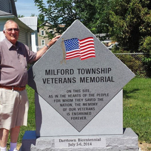 Bill Coombs with veterans' memorial in village square